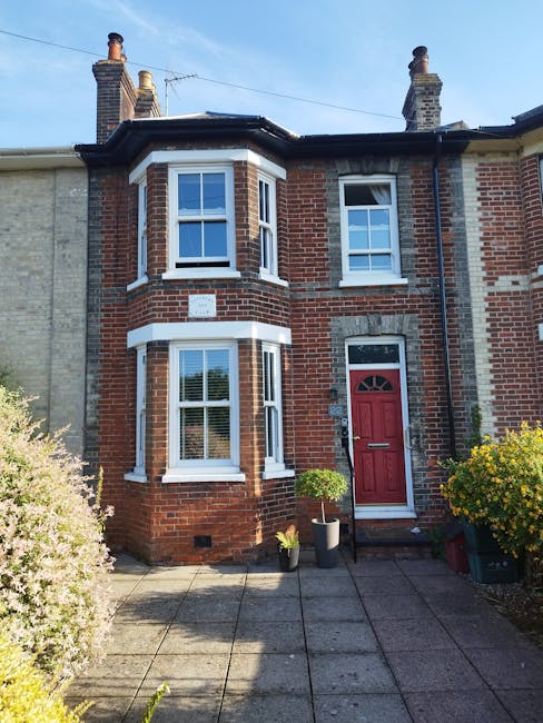 A row of traditional Victorian terrace houses in West Brompton, constructed with red brick and featuring ornate white detailing along the facades. Each property has tall windows, some with bay windows